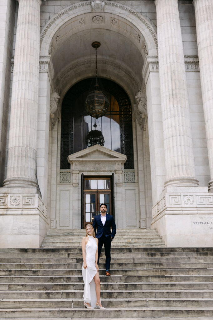 Couple standing on steps of New York Public Library during NYC engagement photos