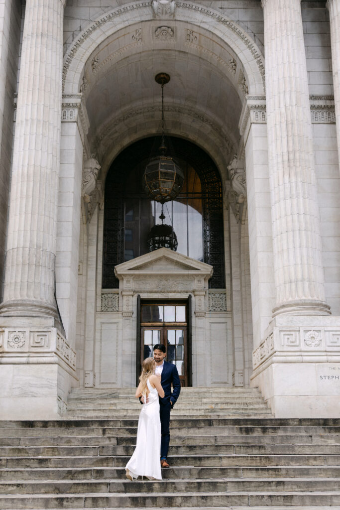Couple embracing on steps of New York Public Library during NYC engagement photos
