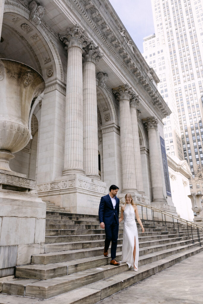 Couple walking by columns outside New York Public Library during NYC engagement photos