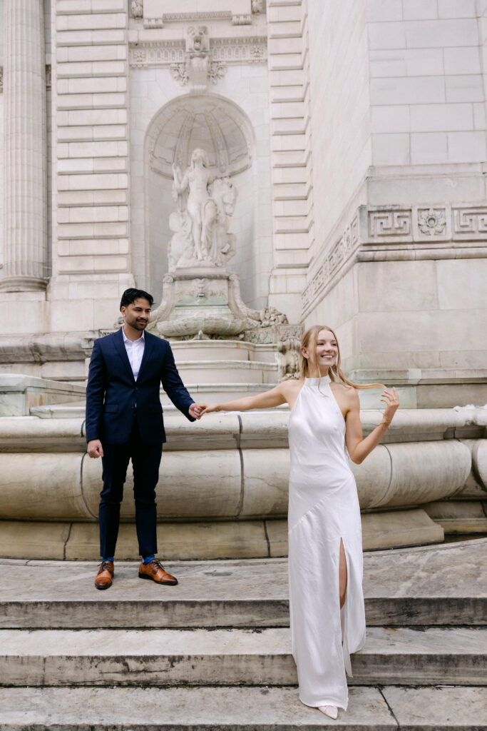 Couple celebrating on steps of New York Public Library during NYC engagement photos