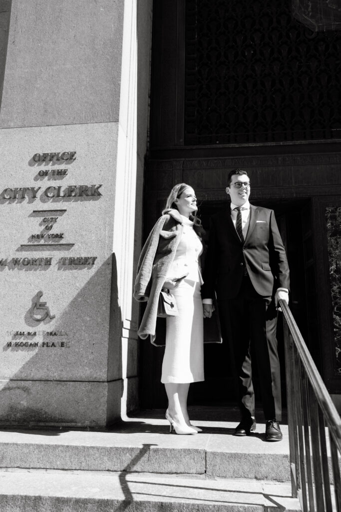 couple exiting nyc city hall courthouse after elopement wedding black and white