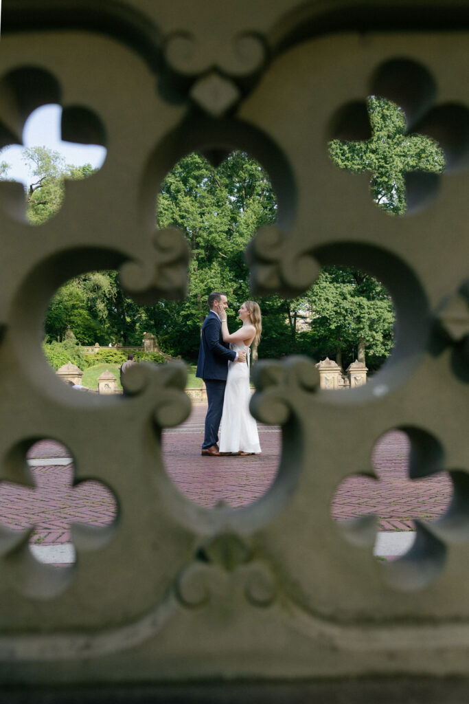 Engaged couple framed through the decorative stonework at Bethesda Terrace during their Central Park engagement session.