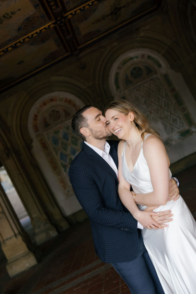 Engaged couple sharing a kiss beneath the tiled ceiling at Bethesda Terrace in Central Park.