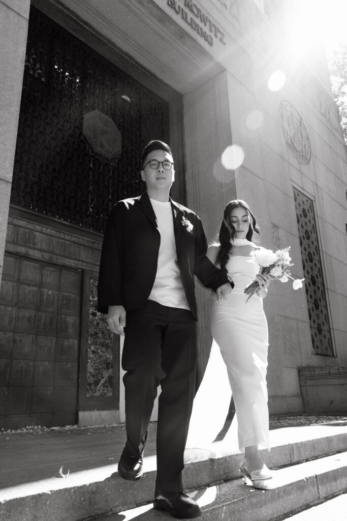 Newlyweds walking down the steps outside the Manhattan Marriage Bureau after their City Hall wedding.