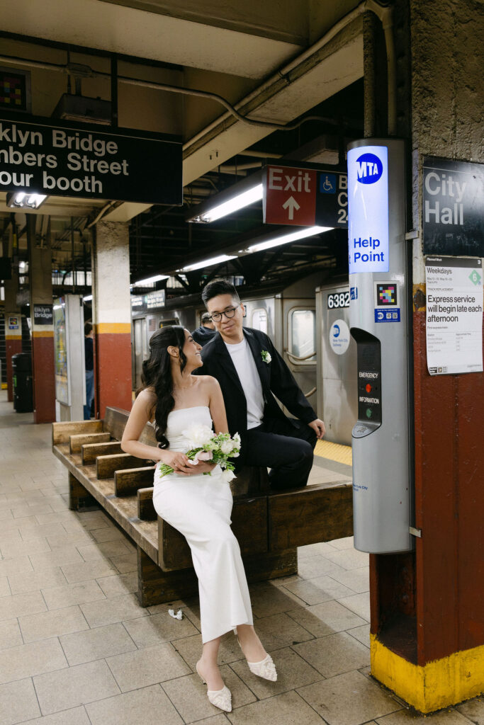 Bride and groom sitting together on a subway station bench after their Manhattan City Hall wedding.