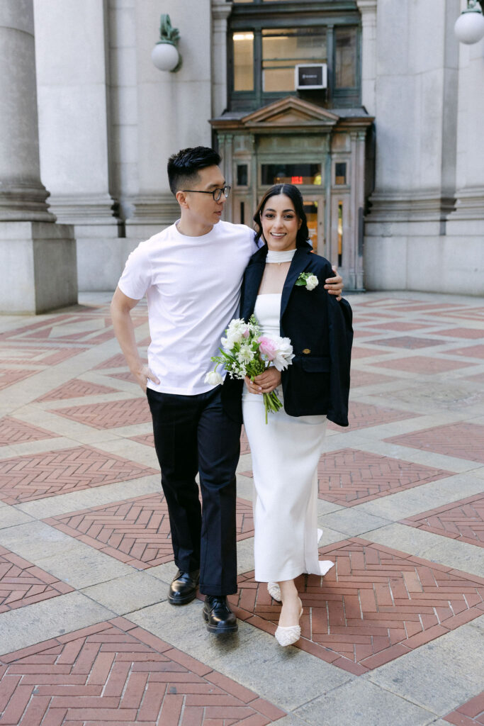 Newlyweds walking arm in arm near the Manhattan Marriage Bureau after their City Hall wedding.