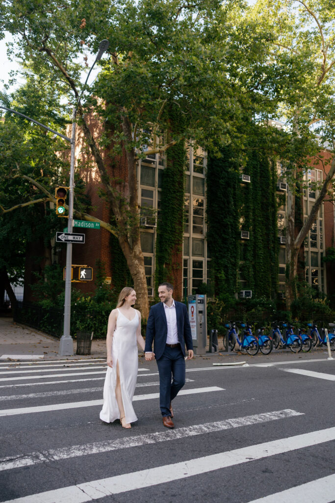 Engaged couple walking together through an Upper East Side crosswalk during their New York City engagement session.